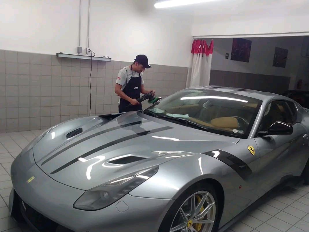 Técnico BioProtec puliendo un Ferrari gris en taller antes de la aplicación cerámica