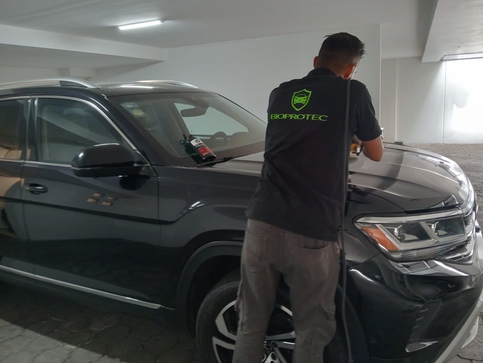 Técnico BioProtec aplicando protección cerámica en una SUV negra