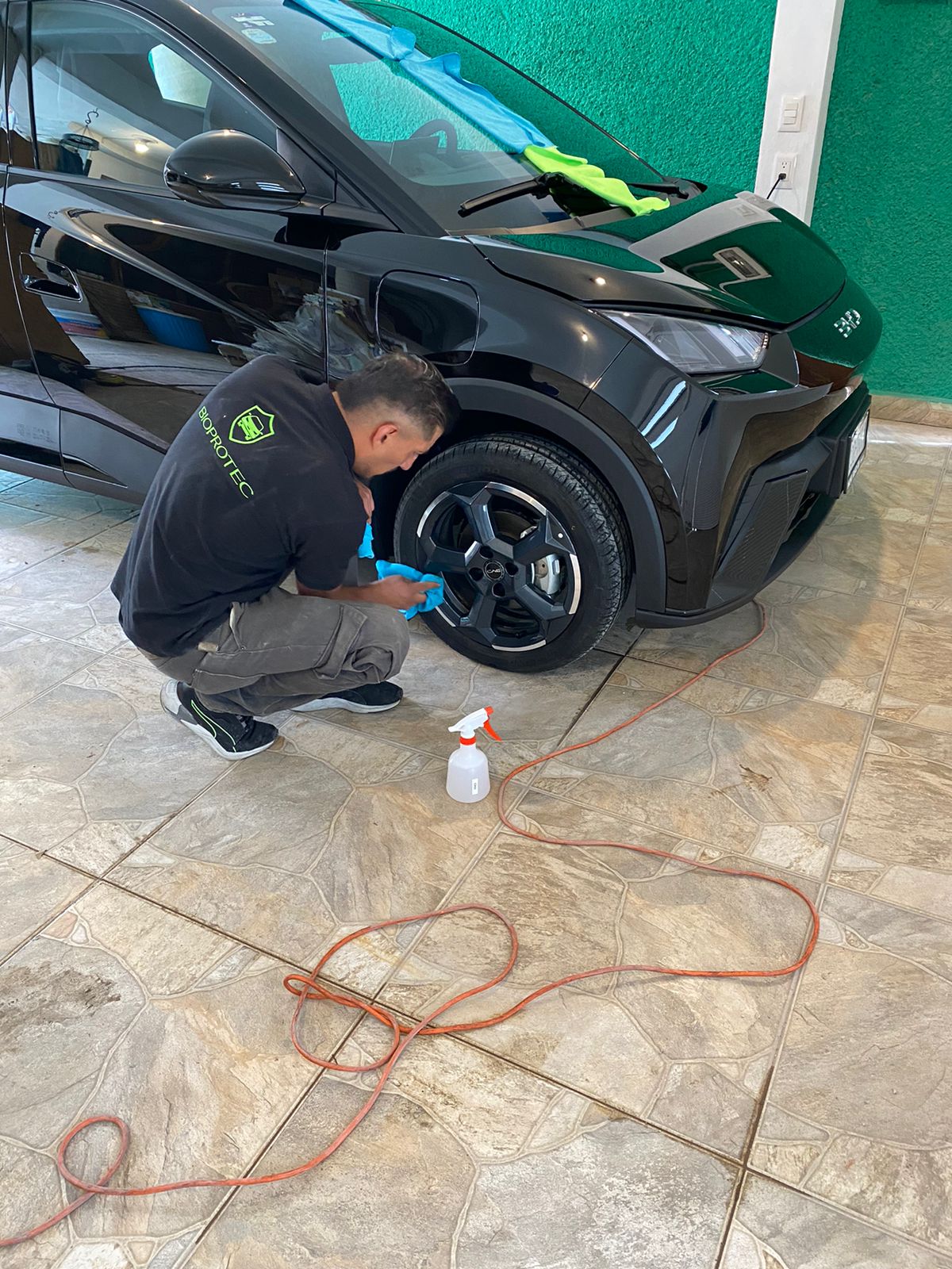 Técnico BioProtec limpiando rines de una SUV negra en cochera